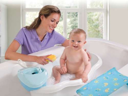 Девушка купает малыша в ванне
